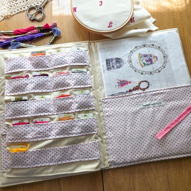 trousse-brodeuse-ouverte-rangement-cartonnettes-fil-a-broder-grille-alice-angelique-la-fee-en-fil Vue d'ensemble de la trousse de brodeuse Alice ouverte à plat, avec compartiments cartonnettes remplis et grille de point de croix dans son emplacement, création artisanale Angélique La Fée En Fil.