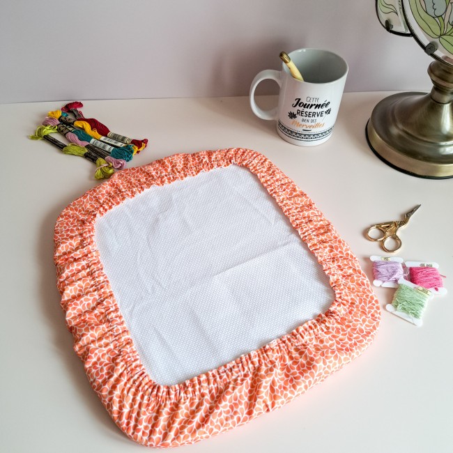 Grime Guard orange Mandarine de la boutique Angélique la Fée En Fil, collection Lumière Végétale, installé sur un cadre nurge avec fils à broder et ciseaux dorés.