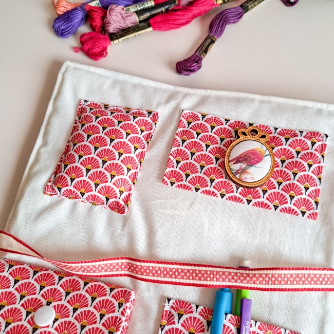 Trousse de brodeuse artisanale en tissu japonais rouge à motifs éventails, ornée d’un médaillon oiseau, création Angélique La fée En Fil, avec poches de rangement et fils à broder colorés.