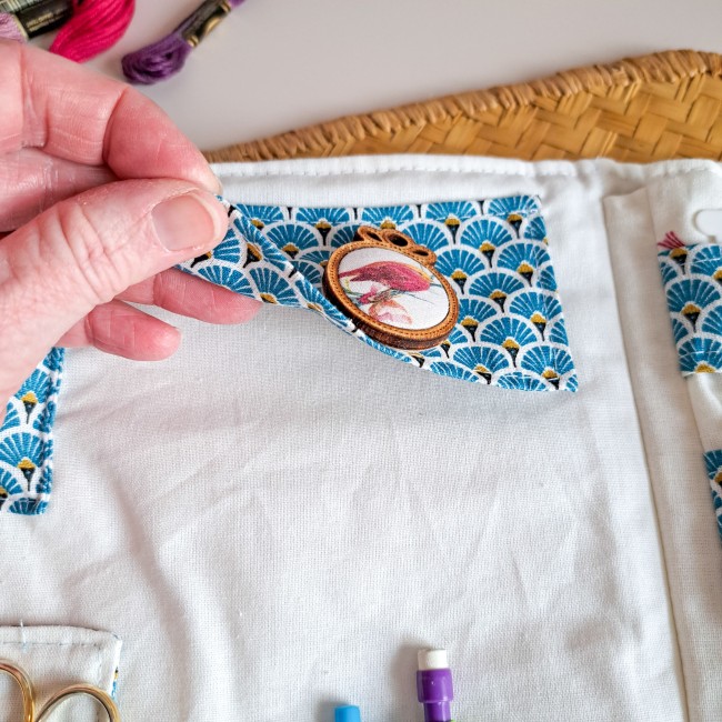 Détail d’une trousse de brodeuse artisanale avec poche en tissu motif éventail bleu et médaillon brodé d’un oiseau – création Angélique La fée En Fil.
