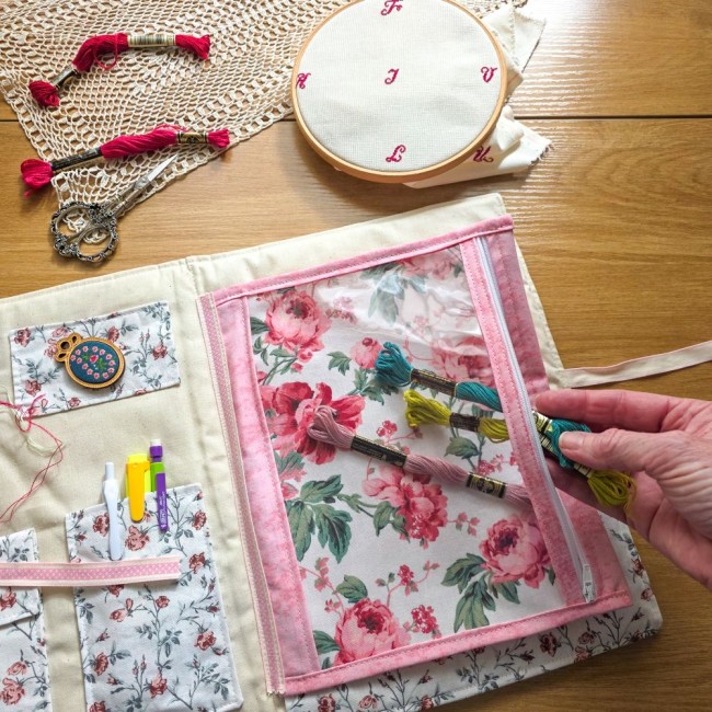trousse-brodeuse-rangement-point-de-croix-echevettes-poche-zippee-sofia-angelique-la-fee-en-fil Main glissant des échevettes de fils dans la poche zippée transparente de la trousse de brodeuse Sofia. Création Angélique La Fée En Fil