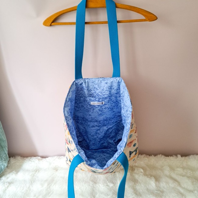 Sac cabas ouvert suspendu sur un cintre. intérieur bleu et sangle bleu. Création Angélique La Fée En Fil