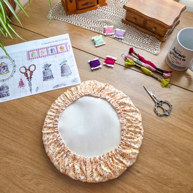grime-guard-sous-bois-dore-tissu-beige-feuillage-tambour-a-broder-rond-angelique-la-fee-en-fil Grime guard rond modèle Sous-Bois Doré en tissu beige à motifs de feuillage ocre, protégeant un tambour à broder sur un bureau en bois avec mercerie par Angélique La Fée en Fil.