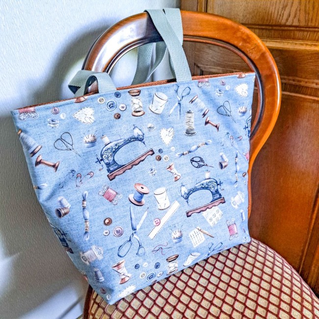 sac cabas elsa posé sur une chaise en bois près d'une armoire. sac en coton imprimé machine à coudre. Création Angélique La Fée En Fil