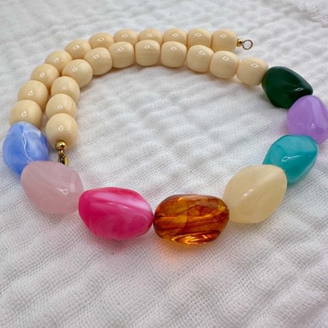 Collier Happy en perles multicolores présenté sur fond textile naturel