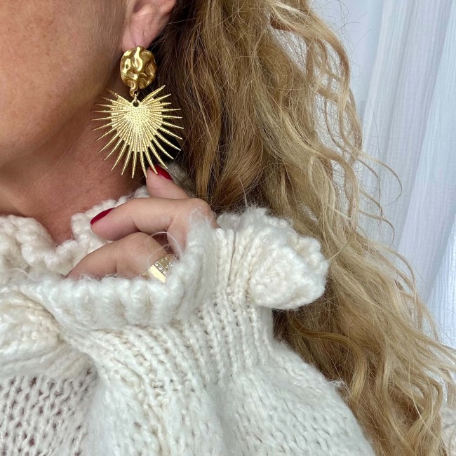 Boucle d’oreille solaire dorée Amaïa portée avec un pull écru – DEBA CREATION