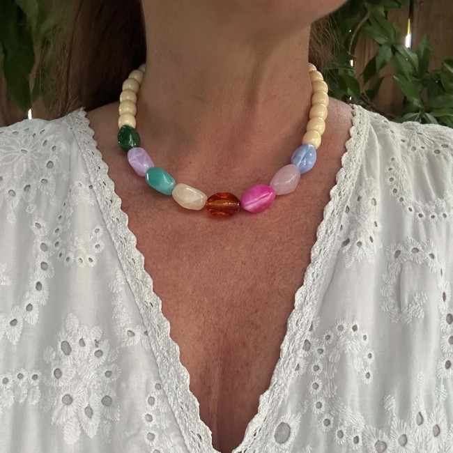 Collier Happy en perles multicolores porté avec une blouse blanche
