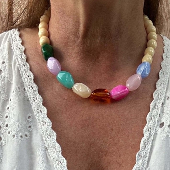 Collier Happy en perles multicolores porté avec une tenue blanche