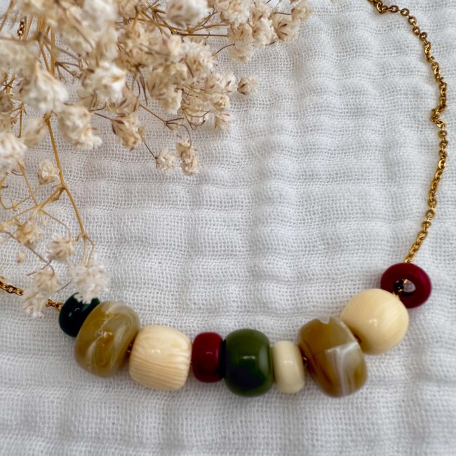 Collier Emma multicolore présenté à plat Collier Emma en perles vertes, bleues, écrues et terracotta présenté à plat sur tissu écru – DEBA CREATION