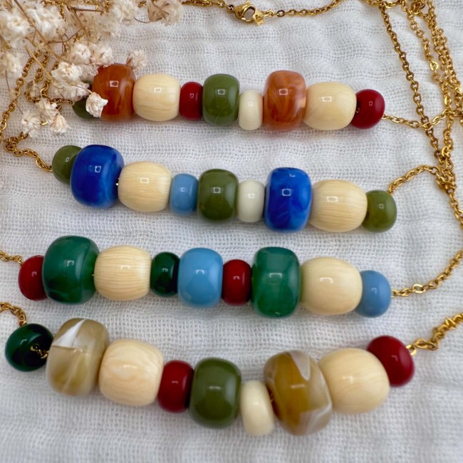 Colliers en perles multicolores sur chaîne dorée Colliers en perles multicolores sur chaînes dorées présentés à plat sur tissu écru – DEBA CREATION