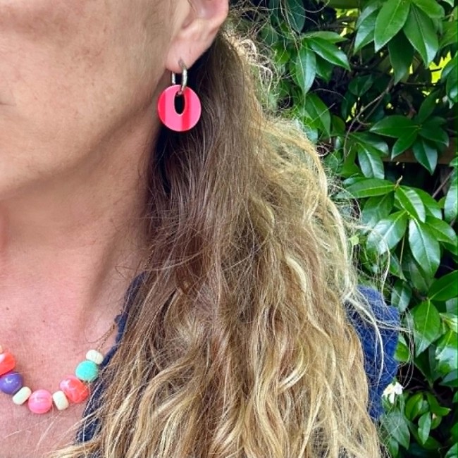 Créoles Capri roses rayées en résine portées par une femme