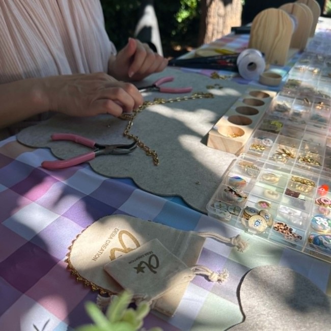 Participante créant son collier lors d'un atelier créatif bijoux