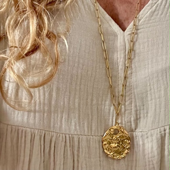 Collier long Mélusine avec pendentif ovale martelé Sautoir Mélusine doré avec pendentif ovale martelé porté sur une robe
