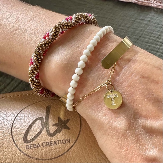 Bracelet permanent doré associé à plusieurs bracelets fantaisie au poignet