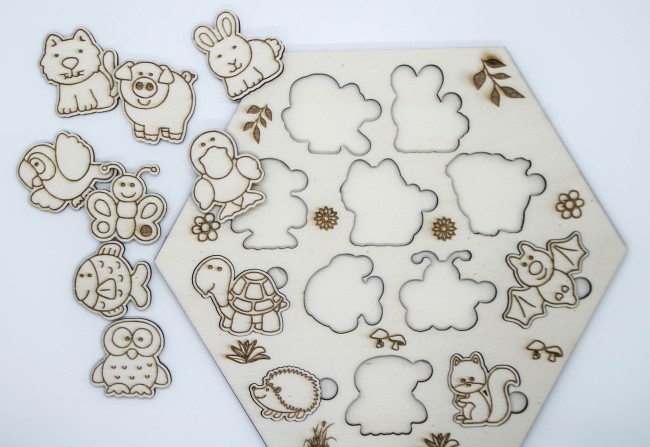 Pièces du puzzle en bois représentant différents animaux de la ferme, posées à côté de la planche.