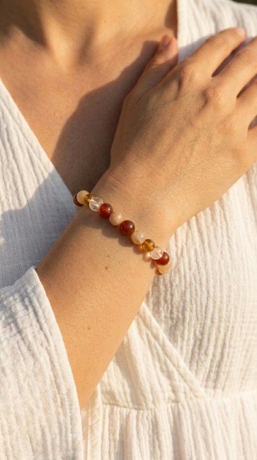 main qui réalise un bracelet en pierres naturelles