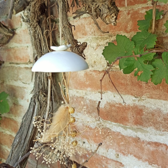Clochette suspendue en porcelaine fleur Clochette suspendue en porcelaine blanche fleur accrochée à une vieille vigne