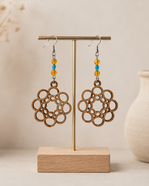 Boucles d'oreilles en bois de palissandre découpées au laser avec motif arabesque, perles orange et turquoise sur présentoir.