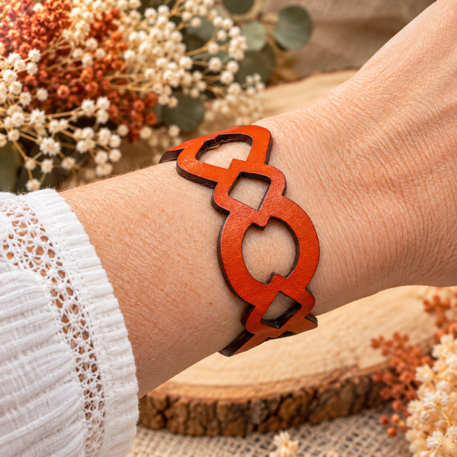 Bracelet en cuir orange ajouré aux motifs géométriques porté au poignet, création artisanale française