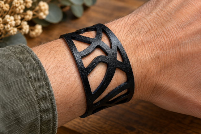 Bracelet homme cuir noir ajouré – Porté au poignet Bracelet manchette homme en cuir véritable noir porté au poignet, large motif abstrait ajouré aux lignes courbes