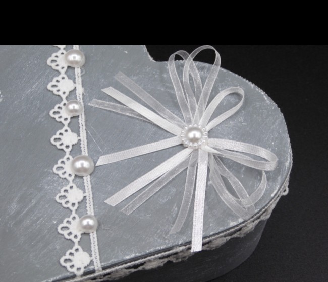 Détail du nœud en satin et des perles blanches sur le couvercle de la boîte à bijoux