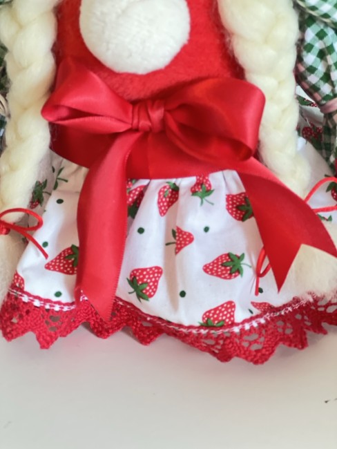 etail-jupe-ruban-poupee-fraise Zoom sur la jupe imprimée fraises, le ruban rouge satiné et les finitions en dentelle de la poupée décorative artisanale.