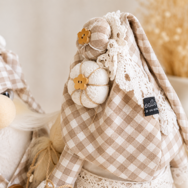 Gros plan sur le bonnet vichy taupe, la dentelle blanche et les petits accessoires décoratifs de la gnome artisanale.