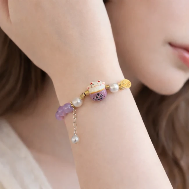 Bracelet porte-bonheur japonais chat Neko mauve en perles de verre porté au poignet chez Modern and Past