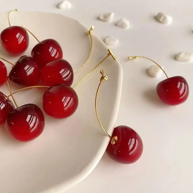 Boucles d'oreilles longues pendantes cerise rouge foncé résine acrylique — vue dans une assiette