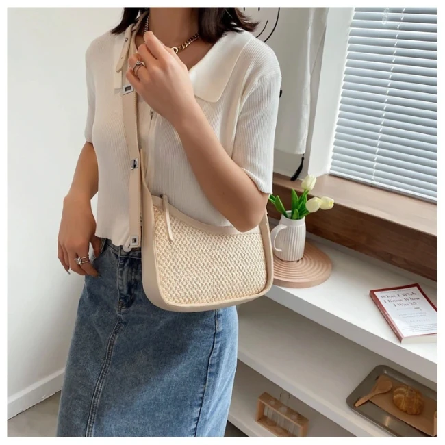 Sac bandoulière beige en paille tissée porté sur une tenue décontractée d'été
