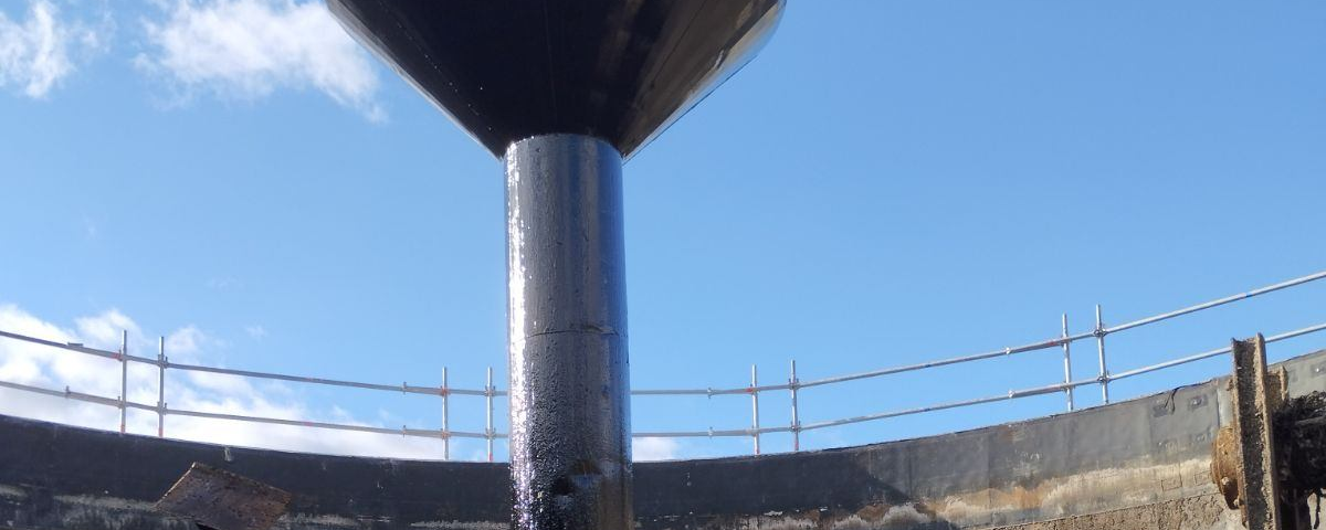 Application d'un revêtement époxy sur un poteau de soutien en béton à l'intérieur d'un méthaniseur.