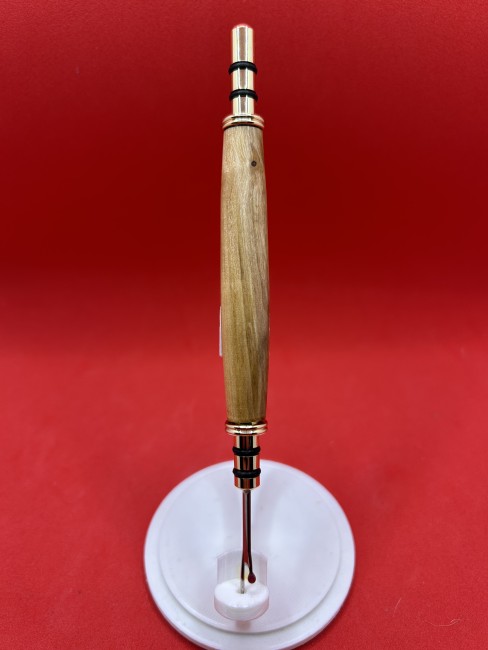 Gros plan sur le découd-vite en bois de mirabellier — texture du bois et insert métalliques dorés