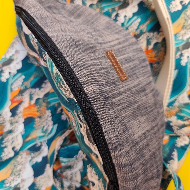 un sac banane bicolore avec une sangle écru posé sur un beau tissu vague 
