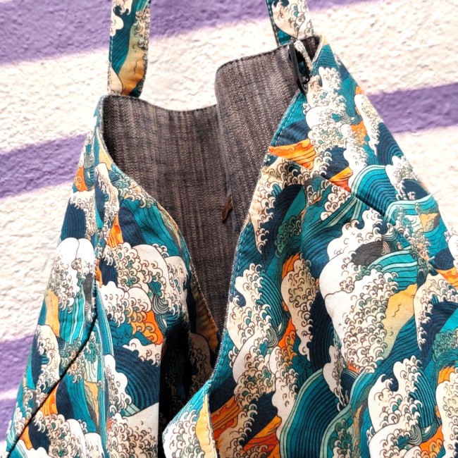 sac cabas réversible Kanagawa fabriqué à Marseille - Artisanat local Jéjé & Lulu zoom sur un sac cabas réversible intérieur en chambray et extérieur en tissu à motif inspiration Hokusaï avec en arrière plan un mur blanc avec un tag trait violet