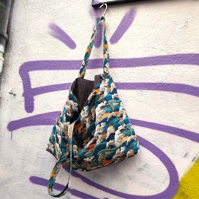 sac cabas réversible Kanagawa fabriqué à Marseille - Artisanat local Jéjé & Lulu un sac urbain et branché illustration vague Kanagawa suspendu devant un mur street art à Marseille au Cours julien en partie entrouvert