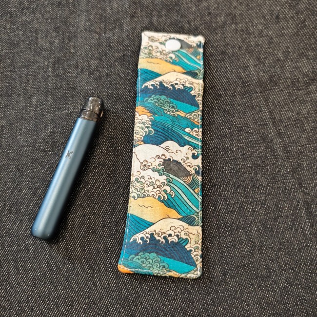 pochette pour petite cigarette electronique - motif vague kanagawa vert canard orange blanc - posée à côté d'une kiwi 2