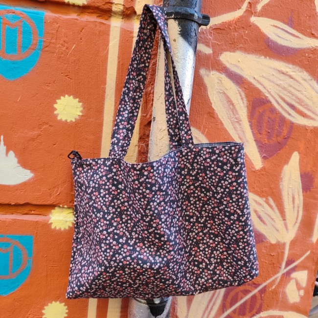 Accessoires textiles de qualité fabriqués à Marseille - Artisanat local - Jéjé & Lulu sac cabas fleuri léger et souple en coton et chambray. accroché dans la rue devant un beau mur avec une illustration de notre dame de la garde, des petits soleils et des grandes fleurs