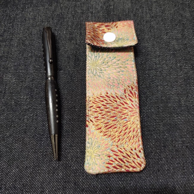 belle petite pochette stylo en tissu à glisser dans son sac à côté d'un stylo en bois en ébène - fleuri doré bordeaux rose bleu