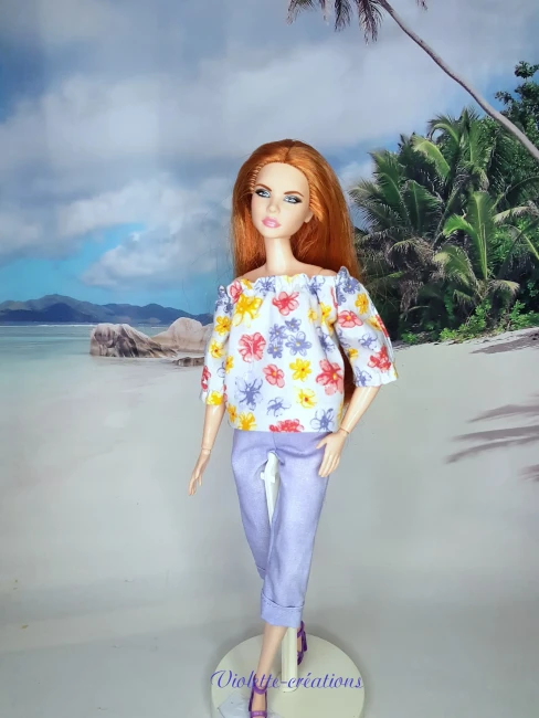 Tenue artisanale en coton pour poupée : Haut floral et pantalon mauve | Violette-Créations Ensemble artisanal Violette-Créations composé d'un haut floral et d'un pantalon mauve en 100% coton pour poupée Barbie