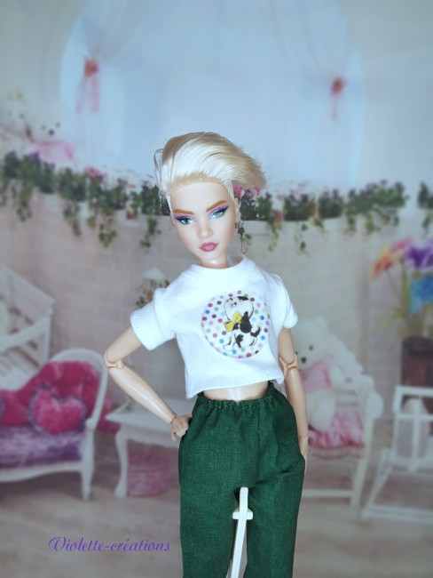 Pyjama en Coton Vert Forêt et Crop-Top pour Poupée Mannequin type barbie (2) Pyjama en coton pour poupée type Barbie composé d'un t-shirt blanc et d'un pantalon vert foncé dans une chambre miniature