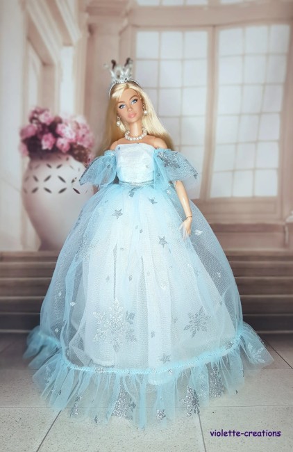 Robe de Princesse Bleu Givré pour Poupée Barbie – Tenue Féérique Poupée barbie portant une robe de princesse bleu clair avec flocons argentés, couronne et bijoux.