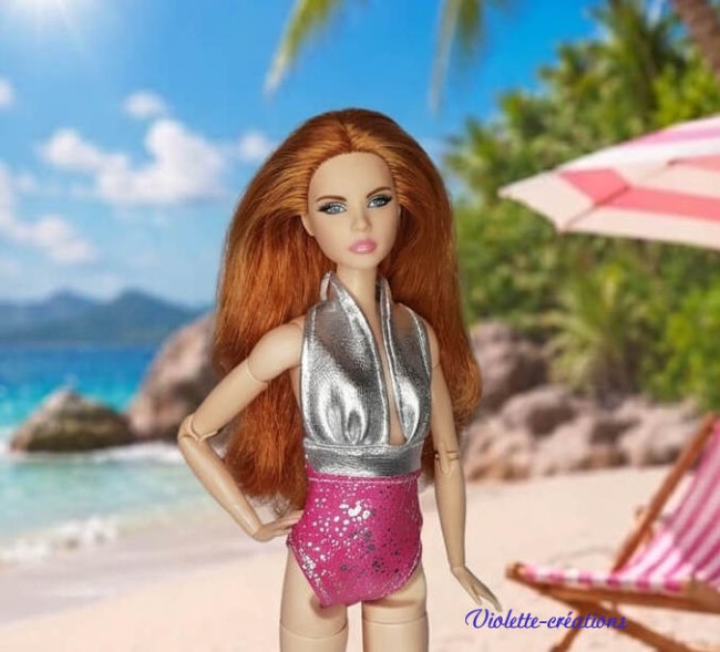 Tenue de plage chic pour poupée mannequin | Violette-créations Poupée mannequin élégante portant une tenue de plage scintillante et rose, présentée sur une plage ensoleillée, création signée Violette-créations.