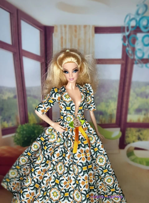 Robe de galla longue pour poupée type Barbie en coton, motif mosaïque géométrique vert émeraude et ocre sur fond écru, décolleté V, manches bouffantes, blason doré et ruban de velours ocre à la taille, création artisanale par Violette-Creations.