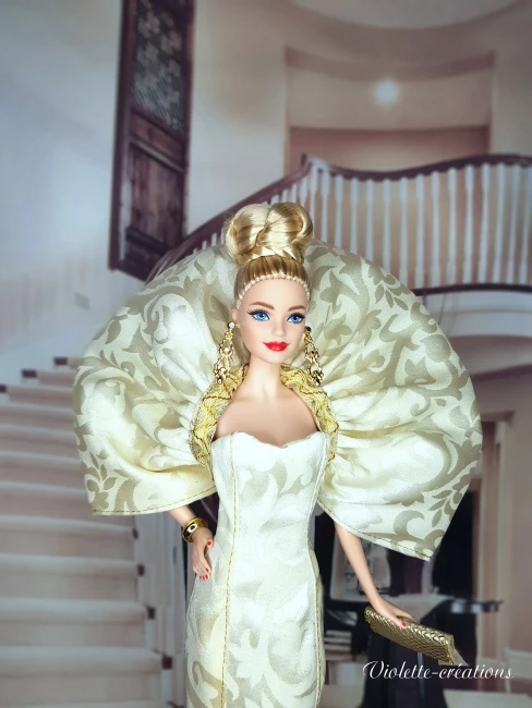 Poupée Barbie de collection en robe de soirée sirène dorée et argentée, posant dans un salon de luxe feutré avec chandeliers.