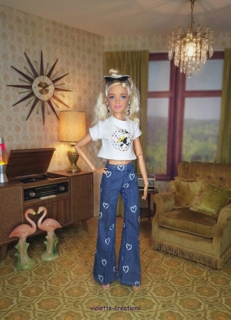 Tenue complĂšte vintage pour poupĂ©e Barbie â Jean Ă cĆurs, blouson papillons, maillot fushia PoupĂ©e Barbie portant un jean bleu Ă cĆurs, un maillot rose fushia, un blouson violet dĂ©corĂ© de papillons et un t-shirt Ă motif sous le blouson.