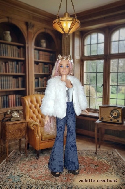 Tenue Mode Barbie : Veste en Fausse Fourrure et Jean Floral Poupée Barbie habillée d'une veste en fausse fourrure blanche, d'un haut argenté et d'un jean évasé avec un motif floral
