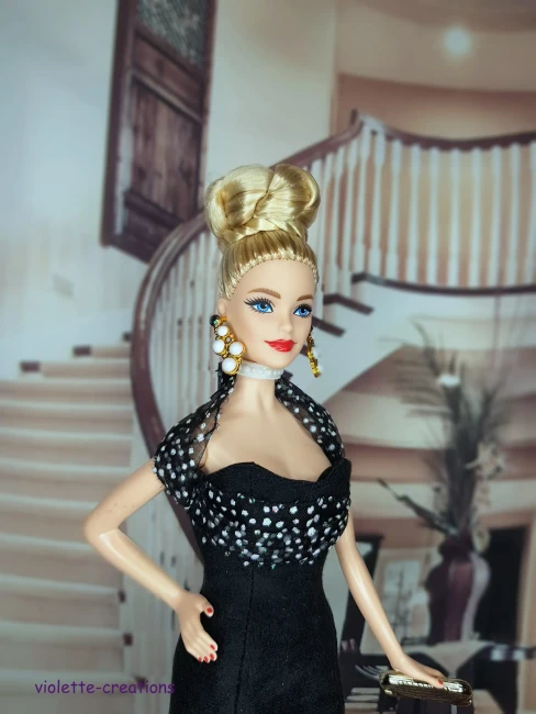 Poupée Barbie portant une robe de soirée longue en suédine noire avec volant en organza à pois blancs et paillettes.