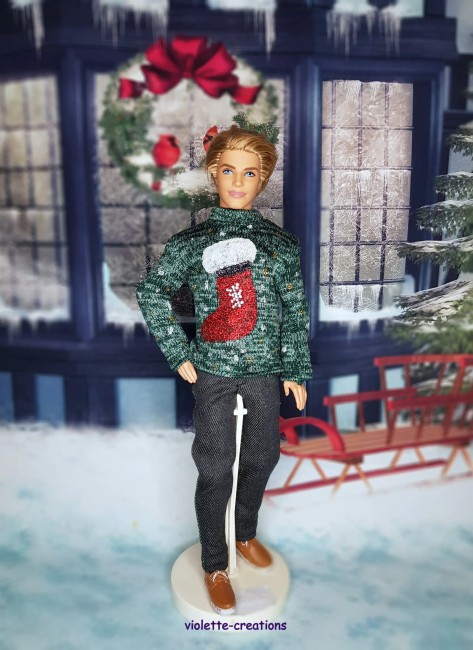 Pull de Noël vert pour Ken – Chaussette rouge scintillante – Violette Créations Ken portant un pull de Noël vert avec une chaussette rouge scintillante.