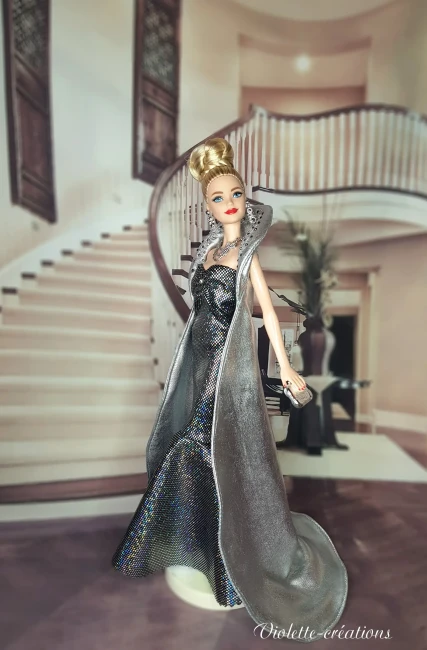 Poupée barbie portant une robe de soirée longue à paillettes avec cape argentée, dans un décor de grand escalier luxueux