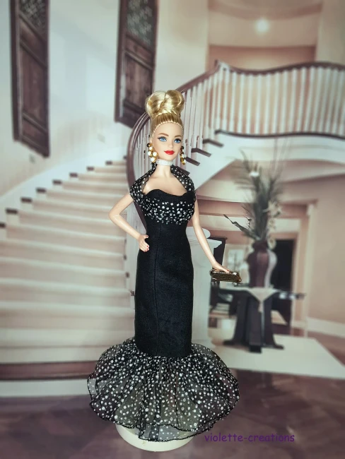 Poupée Barbie portant une robe de soirée longue en suédine noire avec volant en organza à pois blancs et paillettes.